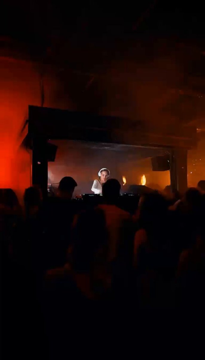 A female DJ performing in a dark club